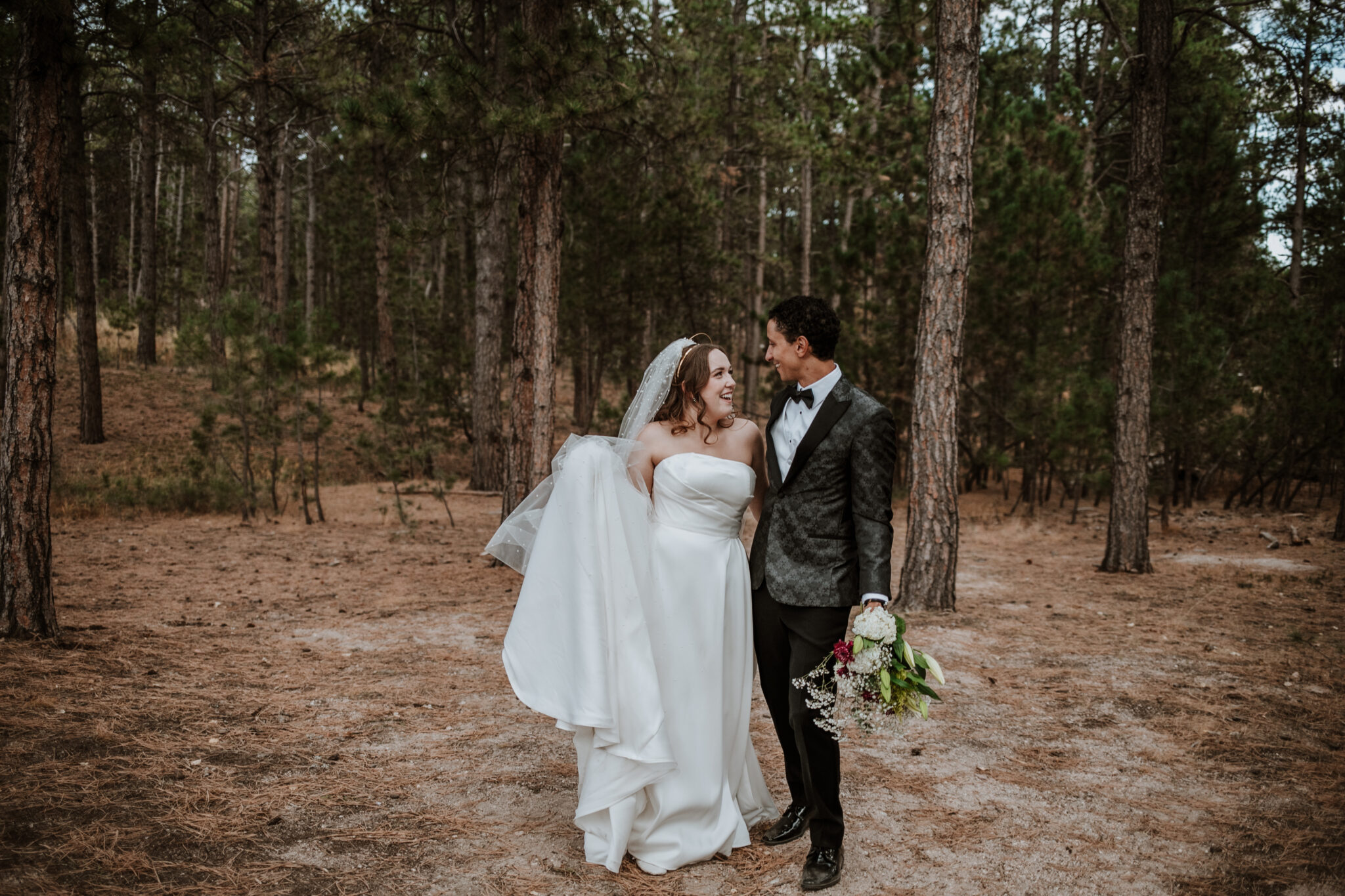 Playful candid of the newlyweds laughing together in the woods at their Colorado Springs wedding
