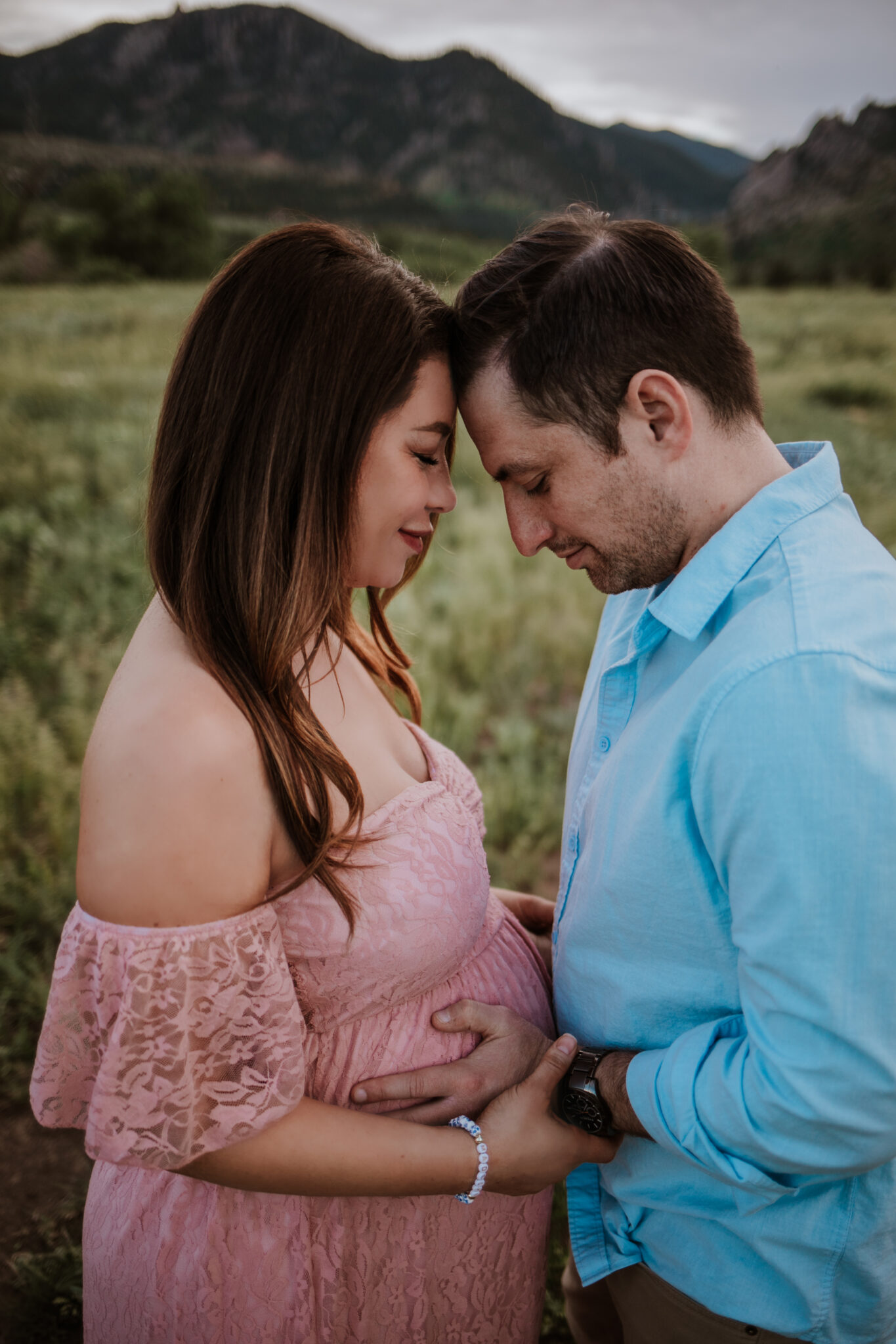 Expecting parents share a quiet moment with mountain views at South Mesa Trailhead maternity session